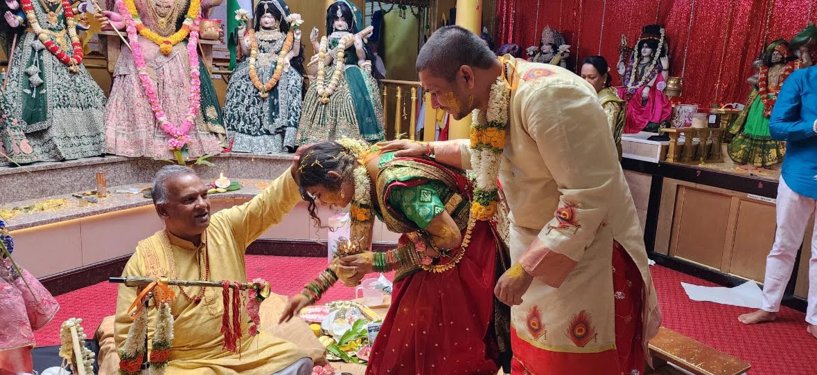 Pandit Doobay blessing a couple during a ceremony in front of the mandir altar